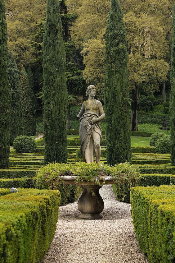 a statue in the middle of a garden surrounded by trees