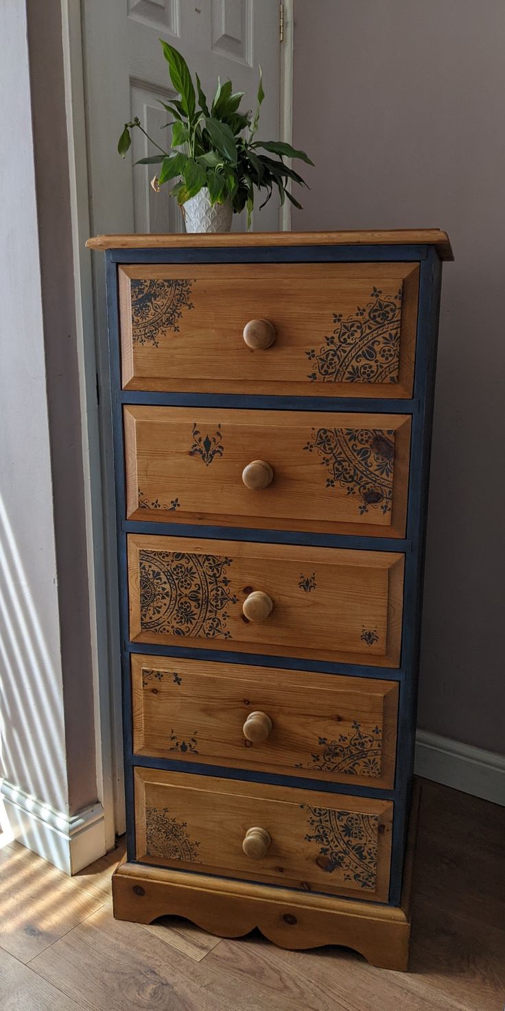 an old dresser has been painted with blue and gold paint on the drawers, along with a potted plant