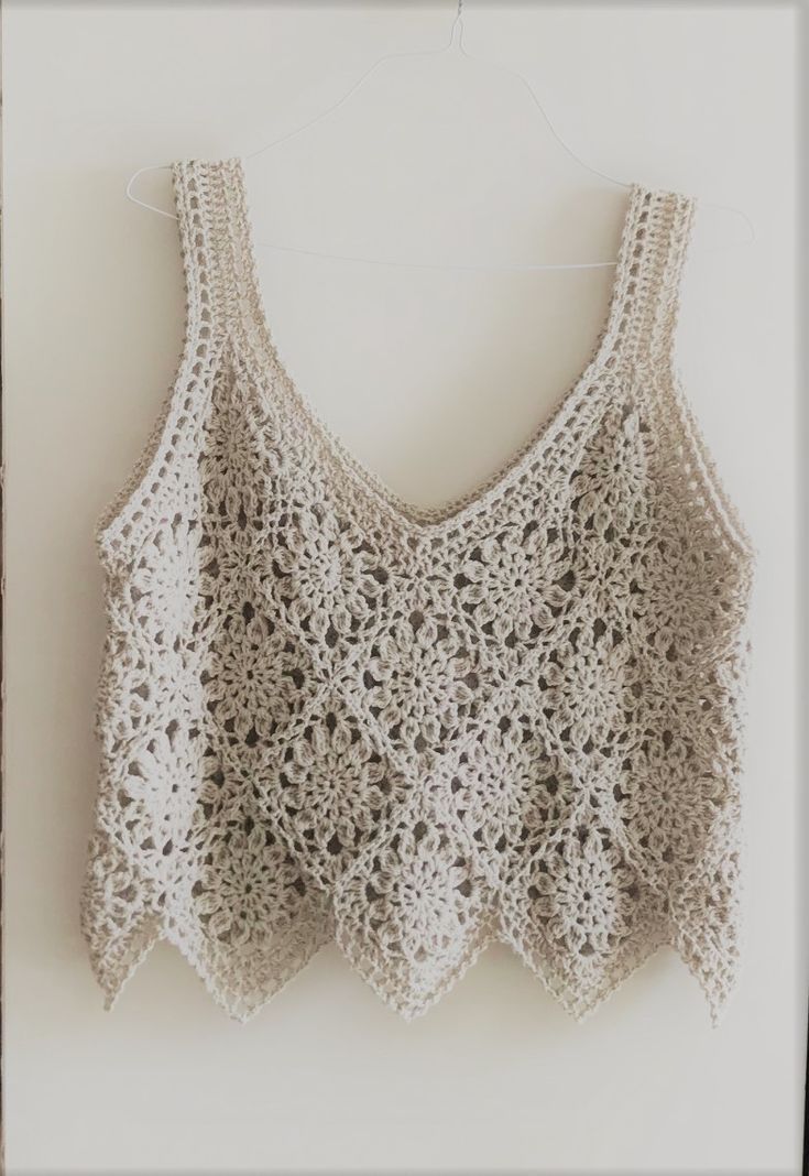 a crocheted top hanging on a wall