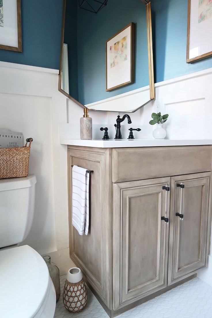 a white toilet sitting next to a bathroom sink under two framed pictures on the wall