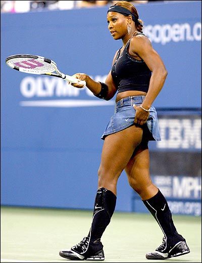 a woman holding a tennis racquet on top of a tennis court with people in the background