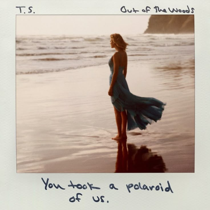 a woman in a blue dress standing on top of a beach next to the ocean