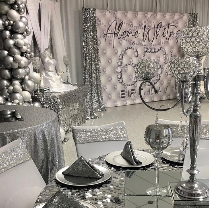 a table set with silver and white decorations