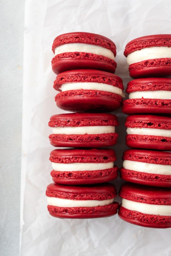 red velvet macaroons with white frosting stacked on top of eachother