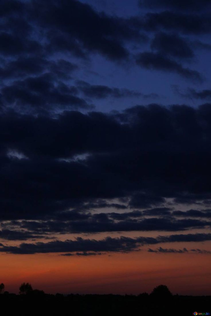 an airplane is flying in the sky at night with clouds and trees behind it as the sun sets