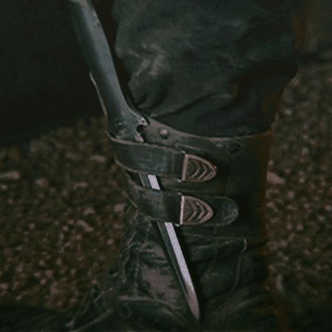 a person wearing black boots and holding a knife