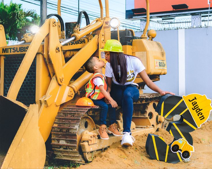 a woman and child sitting on the back of a bulldozer with construction equipment