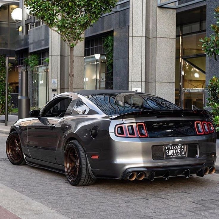 a black sports car parked on the street in front of a tall building with lots of windows