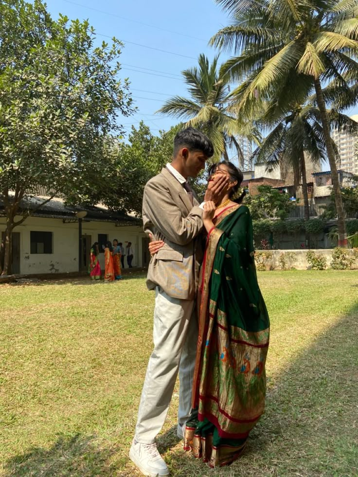 a man and woman standing next to each other in front of palm trees on the grass