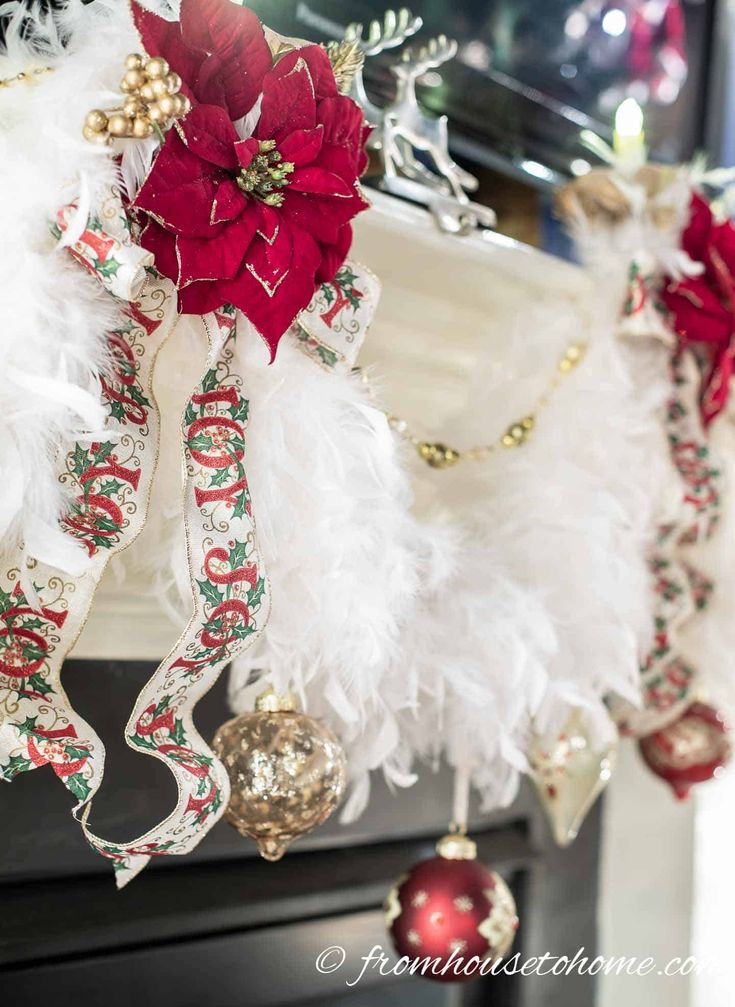 christmas decorations hanging from the ceiling in front of a fireplace with poinsettis