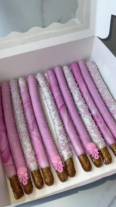 there are many pink and white desserts in the box on the table, ready to be eaten