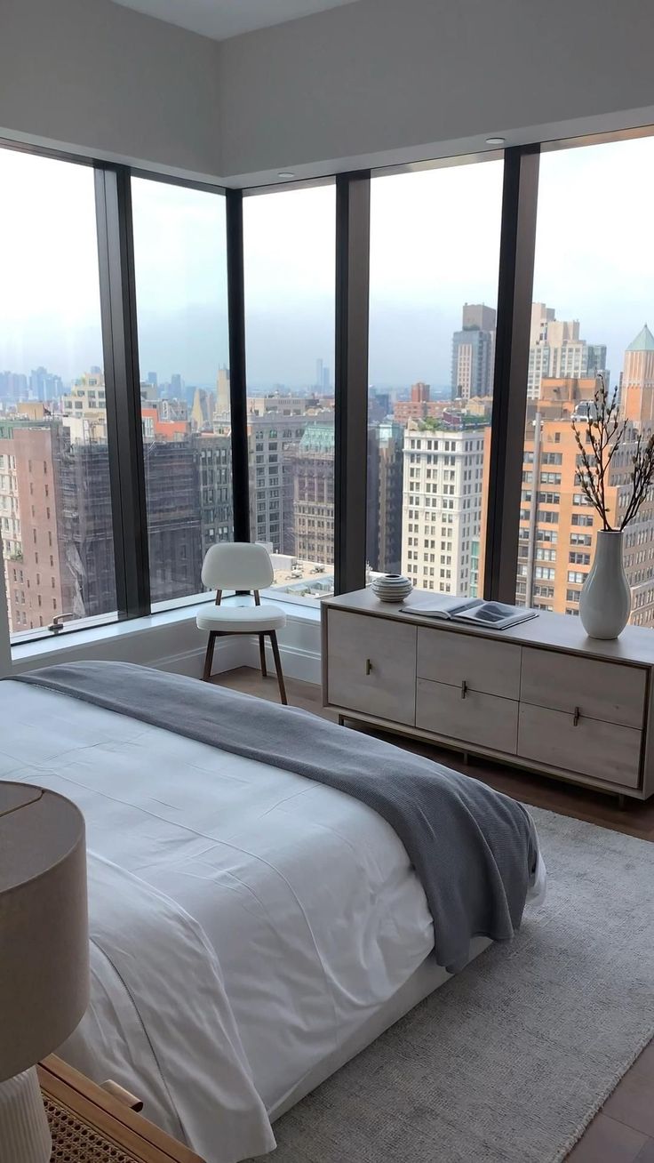 a bedroom with large windows overlooking the city