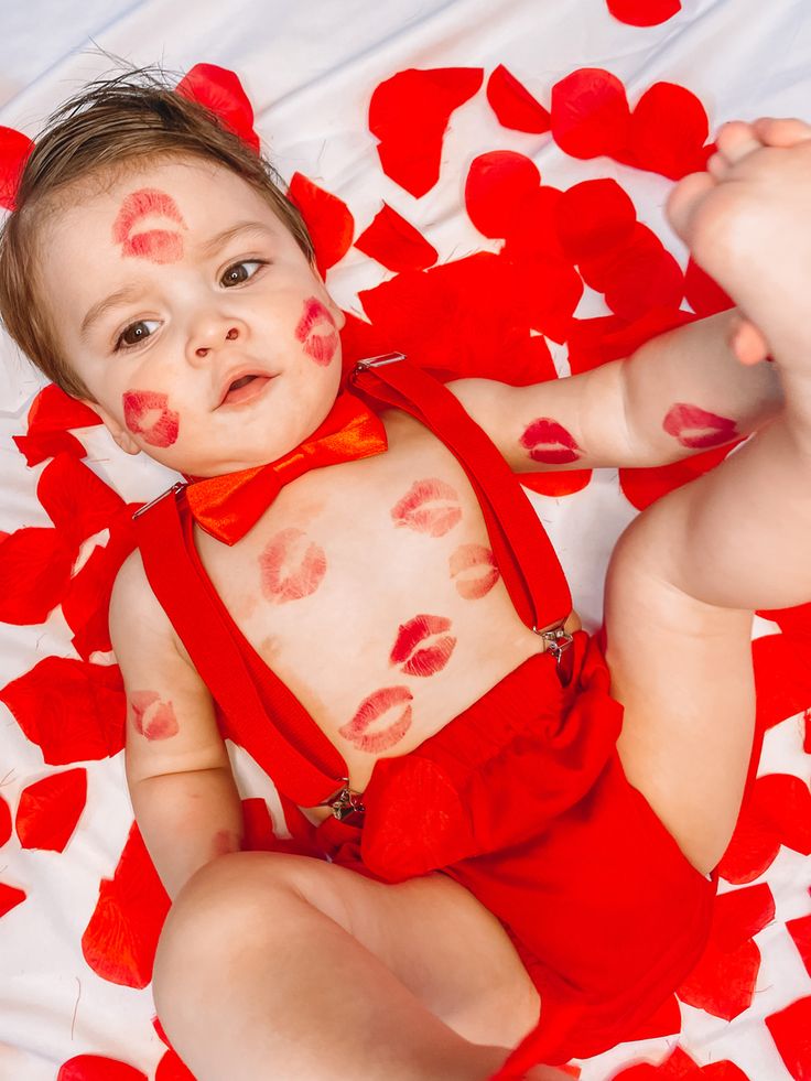 a baby in a red bodysuit with hearts on it