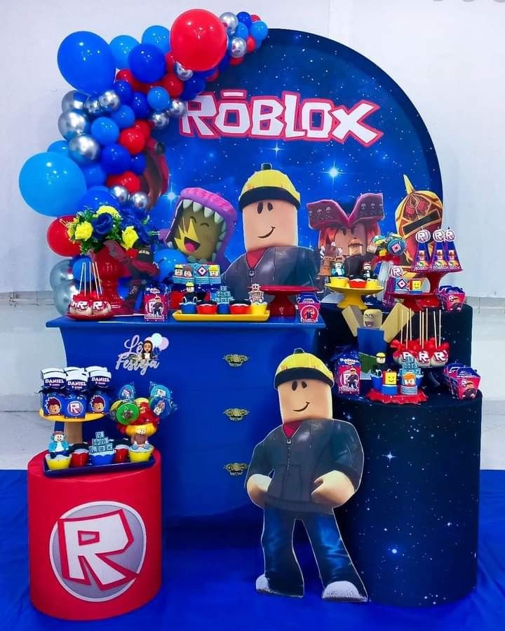 a table topped with toys and balloons on top of a blue cloth covered flooring