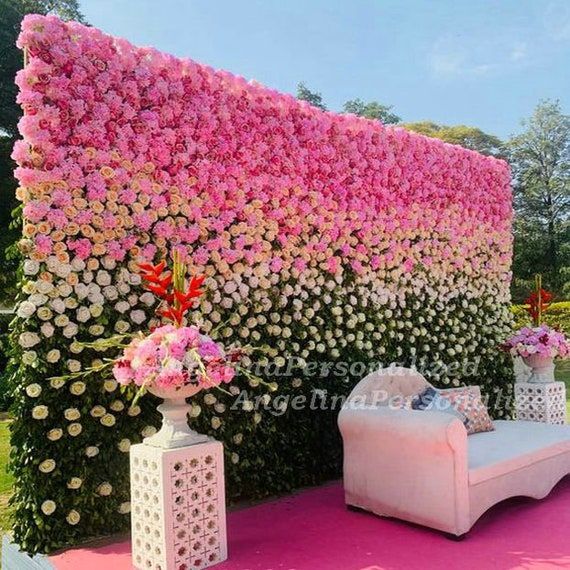 a pink and white flower covered wall next to a couch with pillows on it's back