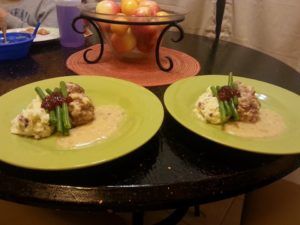 two green plates topped with food sitting on top of a table next to a bowl of fruit