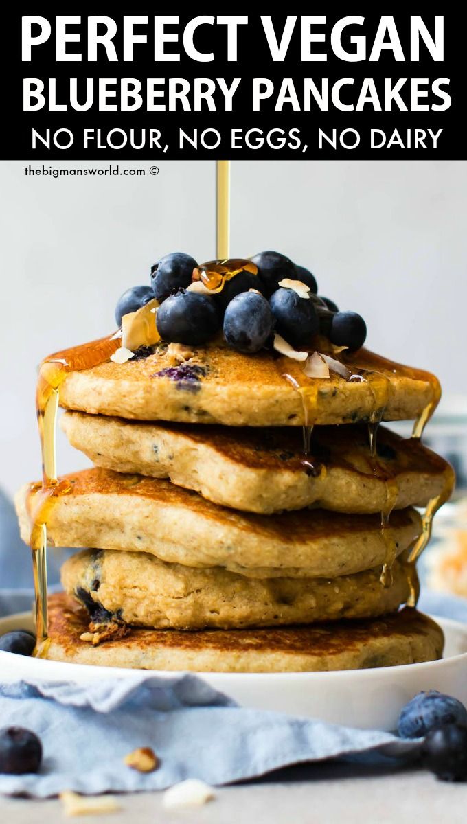 stack of pancakes with blueberries and syrup being drizzled on top