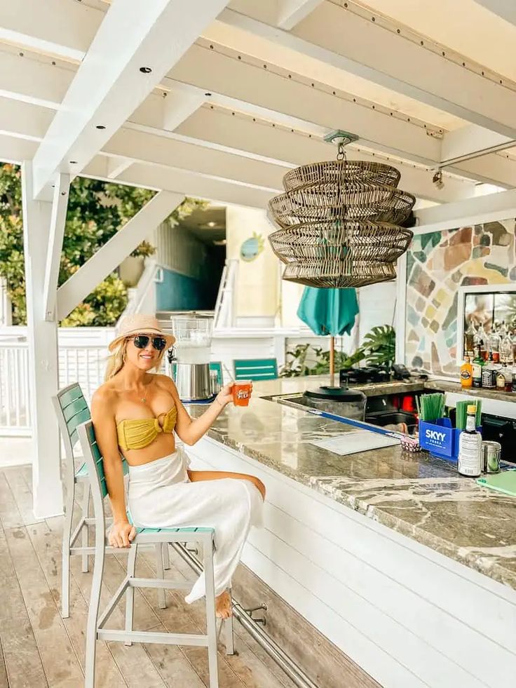 a woman sitting in a chair at a bar holding a drink and looking off into the distance