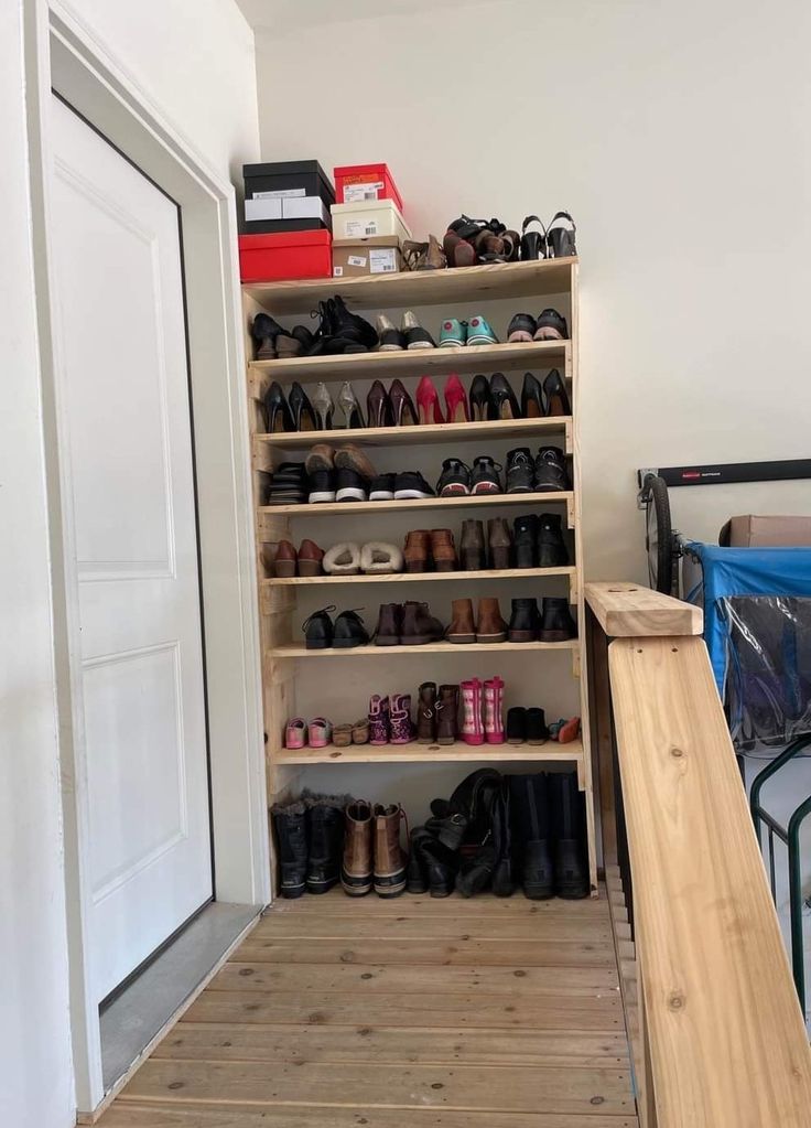 a wooden shelf filled with lots of shoes on top of a hard wood floor next to a bed