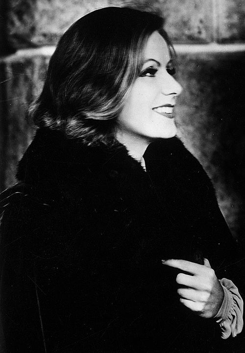 a black and white photo of a woman in a fur coat looking off to the side