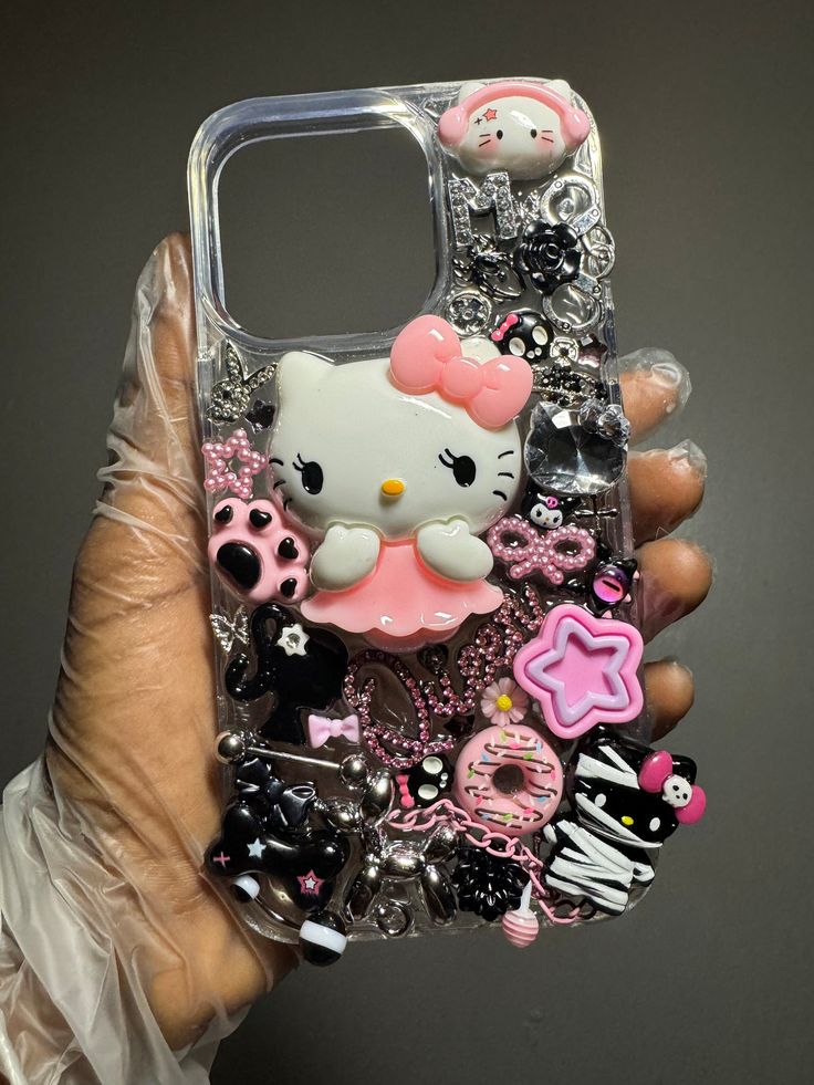 someone holding up their phone case with hello kitty and other items on it, all in clear plastic