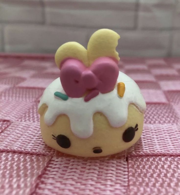 a small cupcake with white frosting and pink decorations on it's top