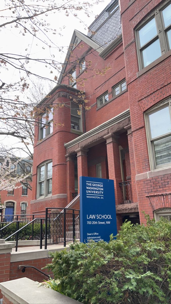 the law school sign is in front of an old brick building with trees and bushes