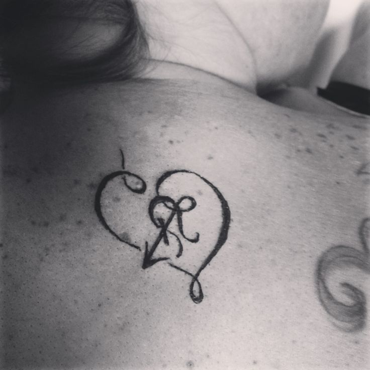 a woman with a tattoo on her back has the letter r in it's heart