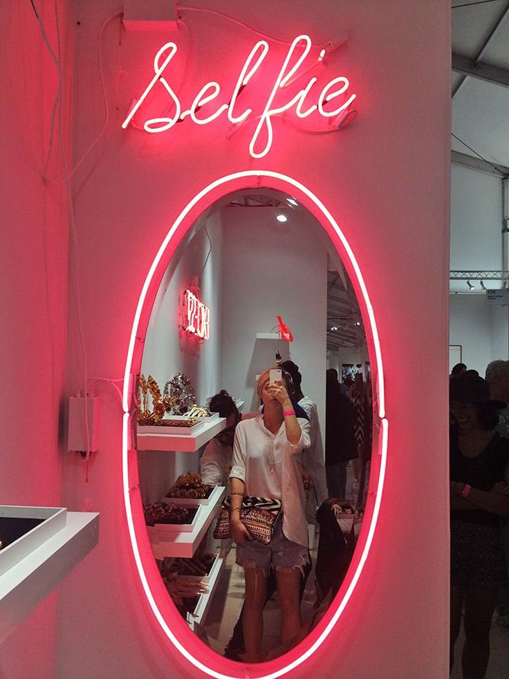 a woman standing in front of a mirror with the word selfie on it's side