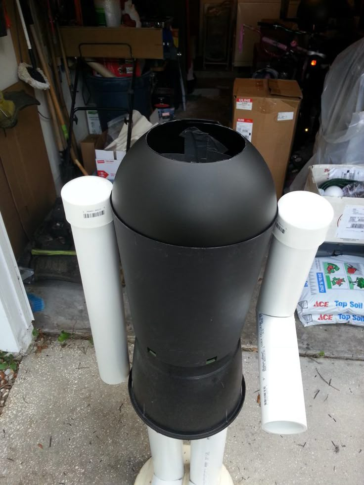 a large black trash can sitting on top of a wooden floor next to other boxes