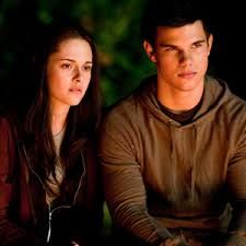 a young man and woman sitting next to each other in front of a forest background