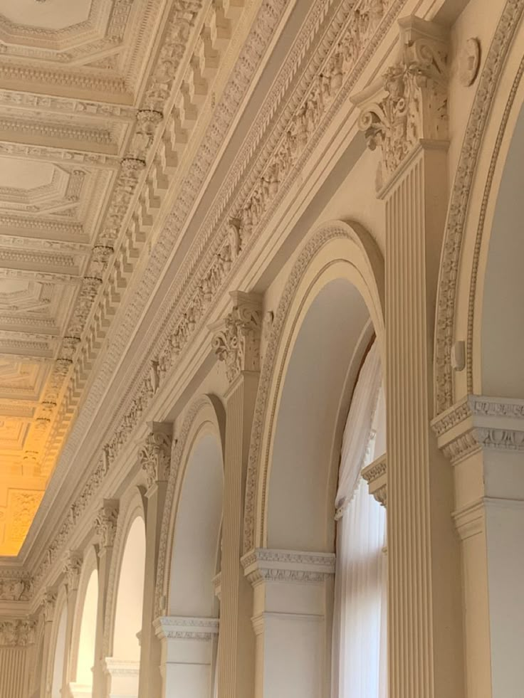 the interior of an ornate building with white columns and arches on either side of it