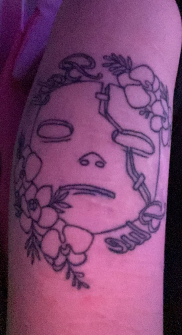 a person with a tattoo on their arm that has a face and flowers in it