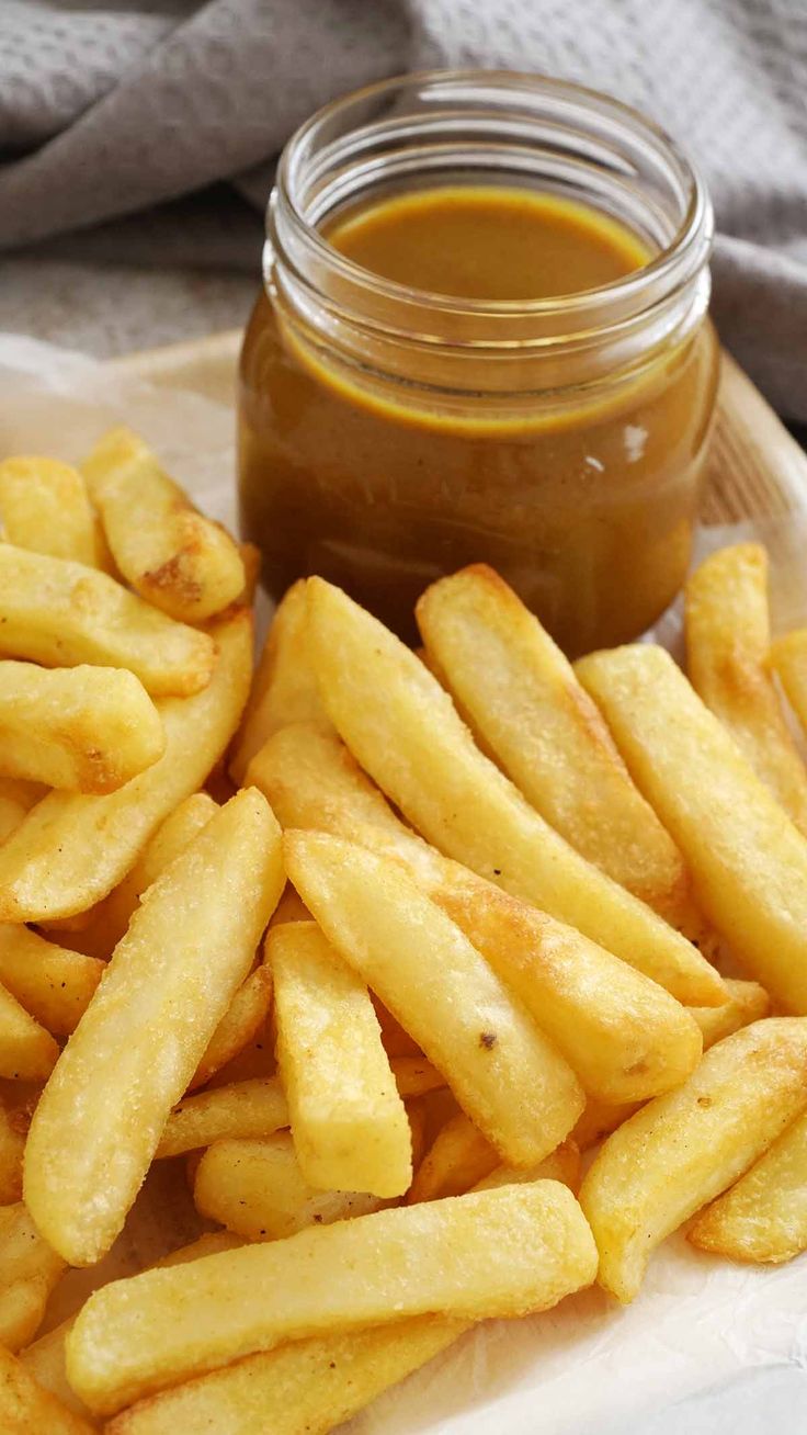 french fries on a plate next to a jar of ketchup and a napkin