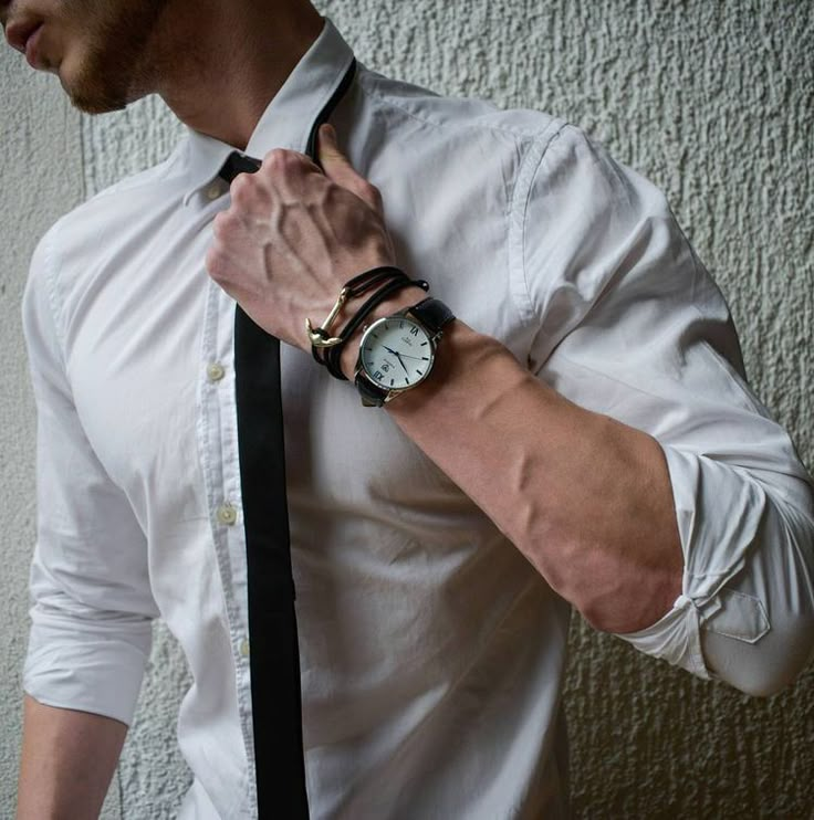 a man wearing a white shirt and black tie with a watch on his left wrist