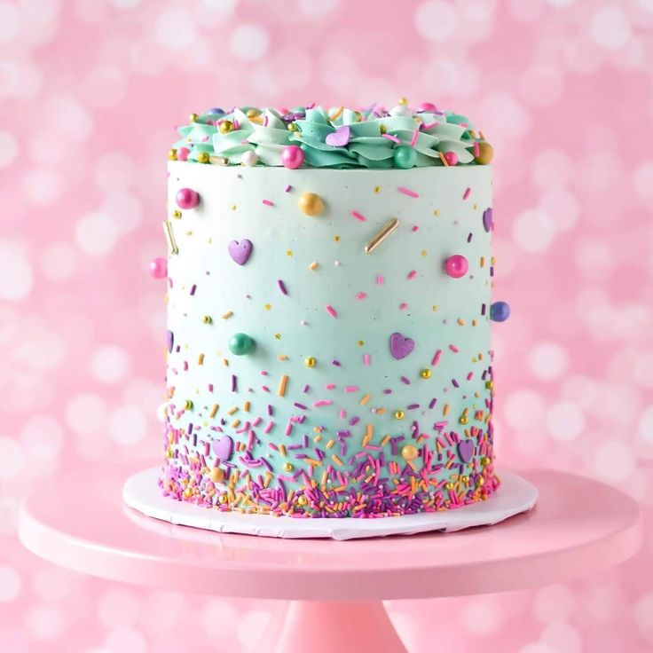 a birthday cake with sprinkles and confetti on top is sitting on a pink table