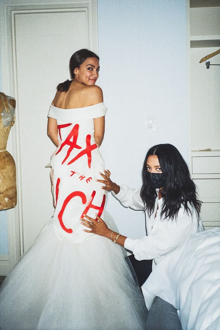 two women dressed in white and red posing for the camera with one woman wearing a dress that says hate to each other