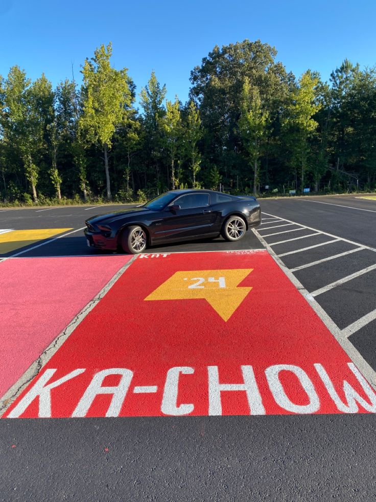 a car parked in a parking lot next to an arrow painted on the ground with words ka - chow