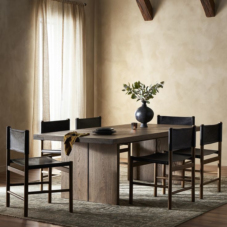 a dining room table with chairs and a vase on it