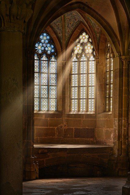 sunlight shining through the windows in an old building with stone flooring and arches on either side