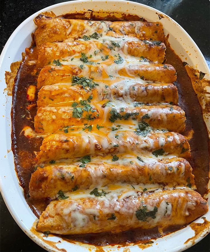 an enchilada dish on a plate with sauce and parmesan cheese