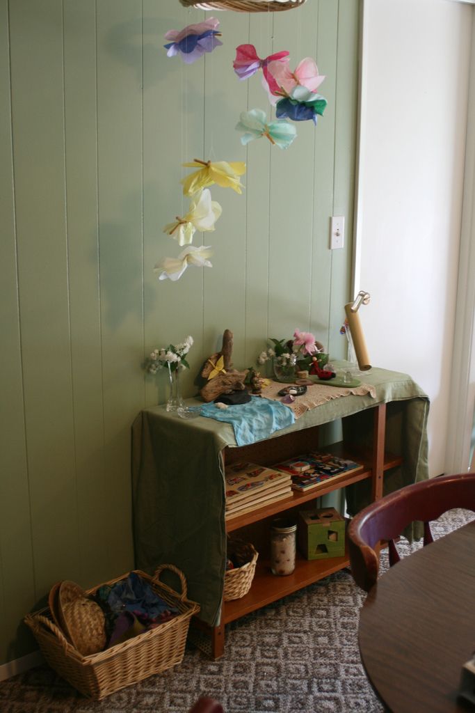 a room with a table, shelf and baskets on the floor in front of it