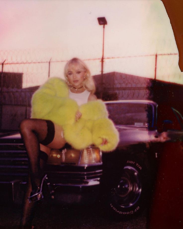 a woman sitting on the hood of a car