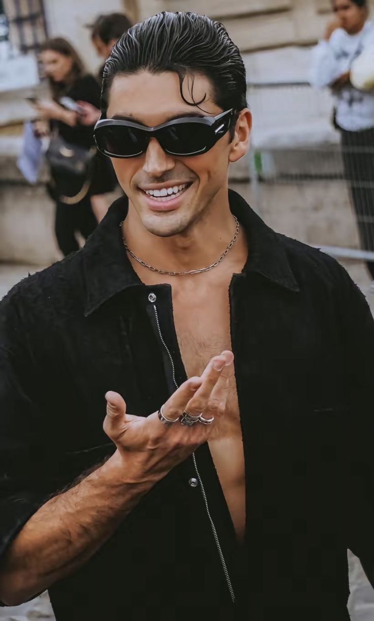 a man with sunglasses and no shirt is making the peace sign while standing in front of some people