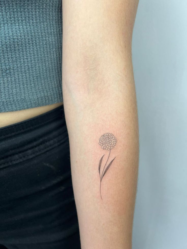 a woman's arm with a small flower tattoo on the left side of her arm