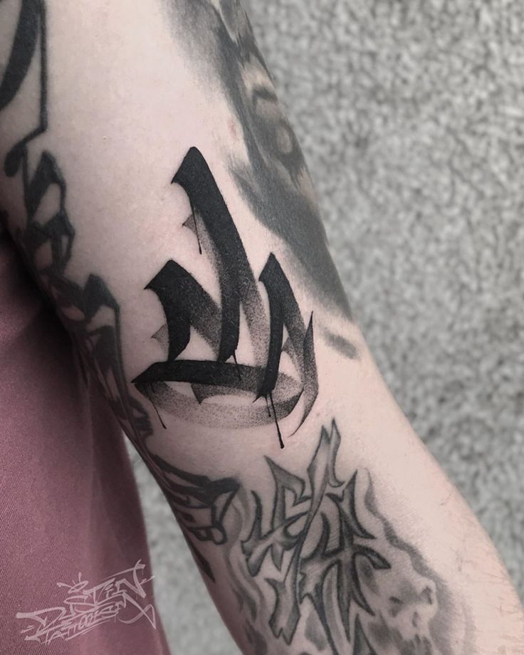 a man's arm covered in black ink with the letter l on it and an arrow