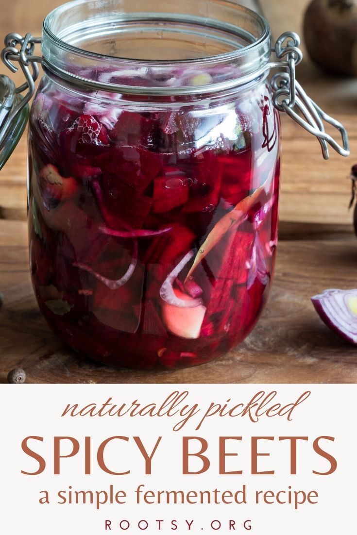 a jar filled with pickles sitting on top of a wooden table next to sliced onions