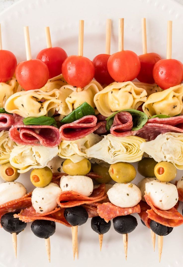 a white plate topped with meat and veggies skewered on toothpicks