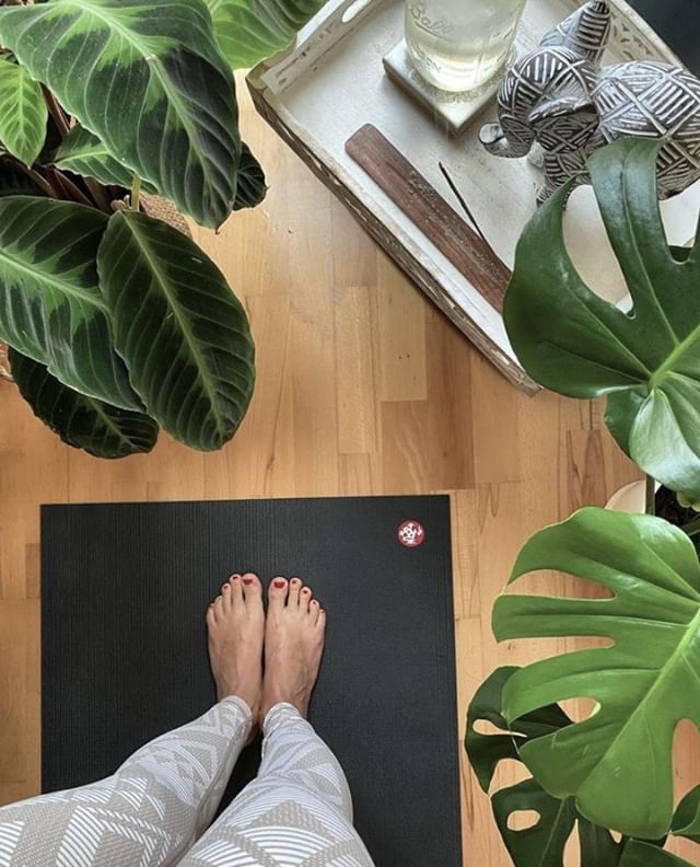 a person is standing on a yoga mat in front of some plants and water bottles