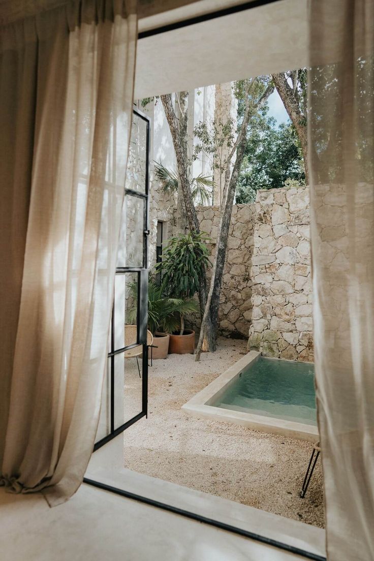 an open door leading to a small pool in the middle of a yard with trees